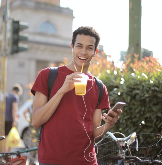 happy-young-man-using-smartphone-on-street-3799835